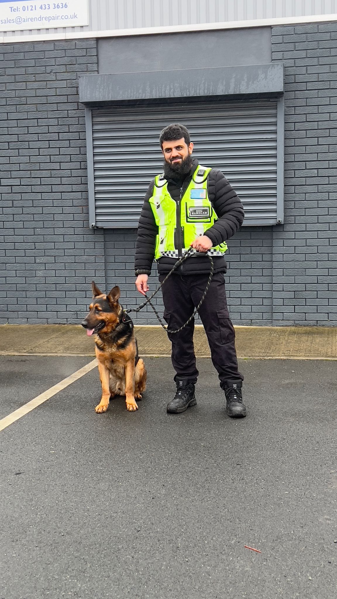 Dog handler and German Shepherd outside commercial premises